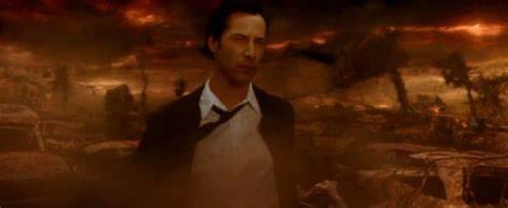 Constantine walks through an ashen, orange apocalyptic wasteland that might be hell