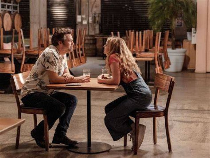Gordon and Ashley lean toward each other over a table in a deserted brewpub in Colin From Accounts